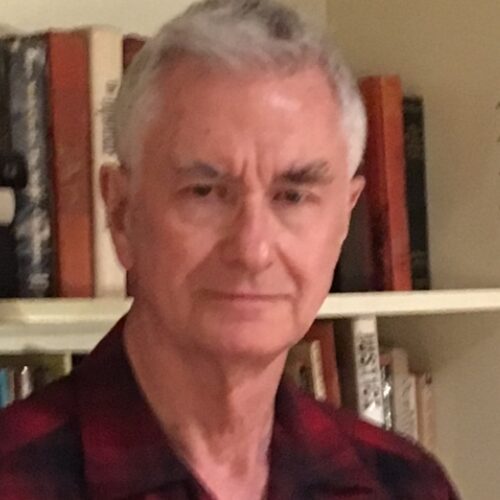 A man with grey hair wearing a red shirt.